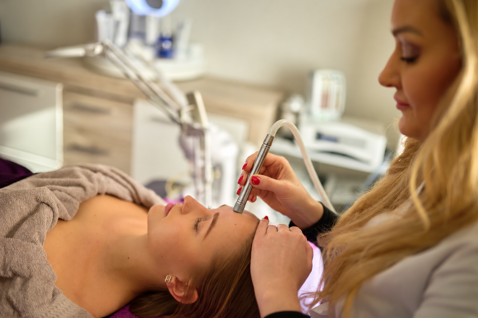 Jasmin bei einer Microdermabrasion mit Chrom-Handstück an der Stirn einer Kundin